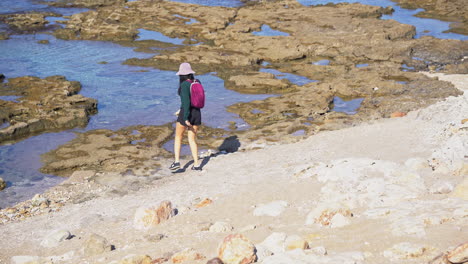 una mujer joven camina hacia el mar en shekmona, haifa, israel