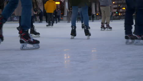 crowded skating rink in an urban setting. still shot of beginner skaters feet gliding around the rink.
