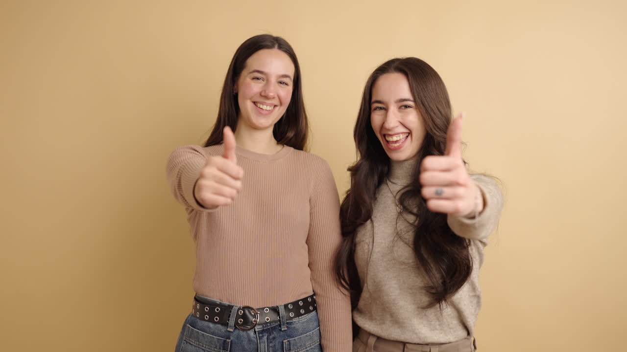 Happy young friends showing thumbs up sign