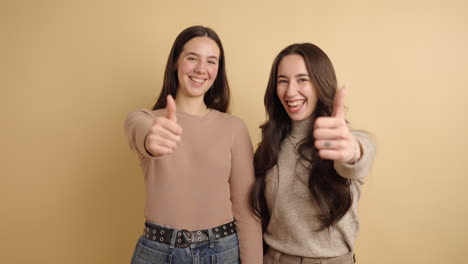 happy young friends showing thumbs up sign