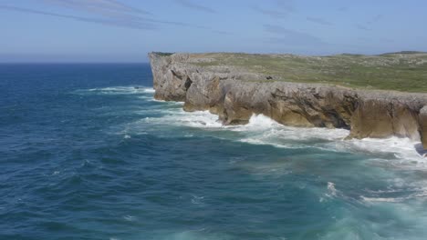 Stunning-blue-bufones-de-pria-asturias-spain-sea-cliffs-and-crashing-waves,-Aerial-orbit-parallax