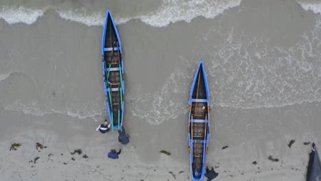 bird's eye view of currach boats launched into water as paddlers enter and sit down