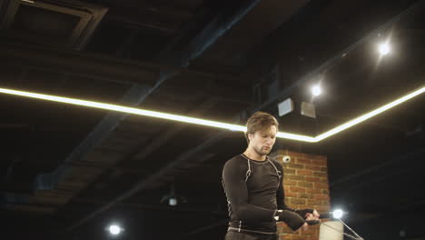 Active-boxer-using-jump-rope-on-boxing-ring.-Sport-man-doing-exercises-at-gym