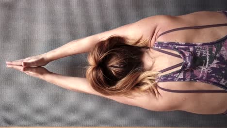 looking down on the back of woman with her hands clasped above her in a yoga pose, then rising up and stretching