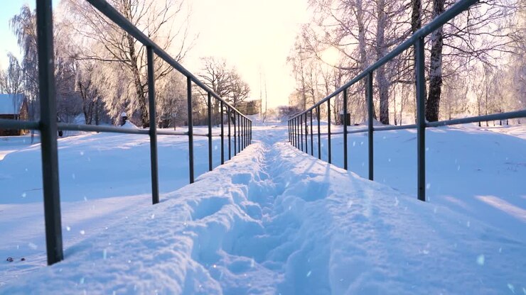 Stålgelænder på landlig bro til fodgængere, dækket af dyb sne