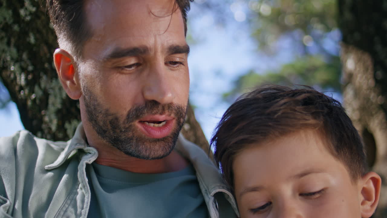 Bonding family reading fairytale at fresh air closeup. Kid relaxing at forest