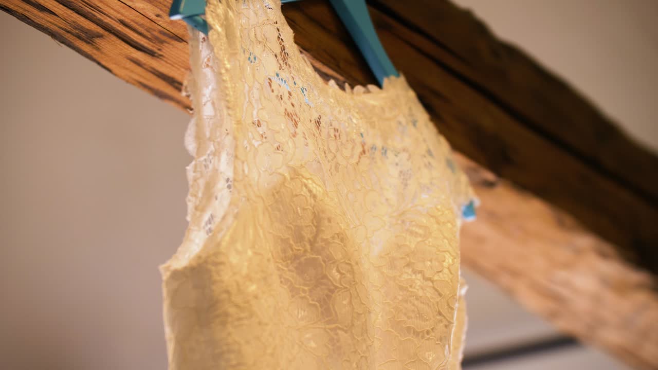 Close-up of a delicate lace garment hanging from a wooden beam