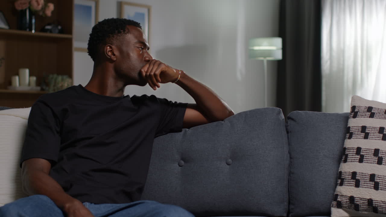 Unhappy And Depressed Young Man Sitting On Sofa At Home Looking Anxious And Worried Resting Head On Hand 1