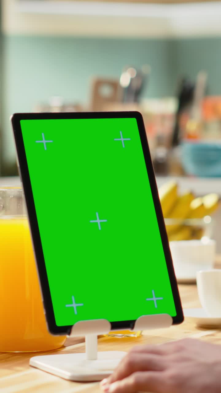 Video verticale. Mockup in chroma key sullo schermo del tablet in cucina su un tavolo di legno