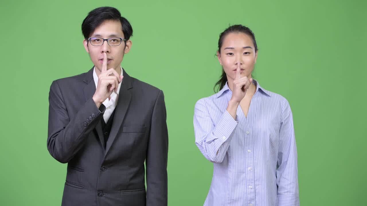 Young Asian business couple with finger on lips together