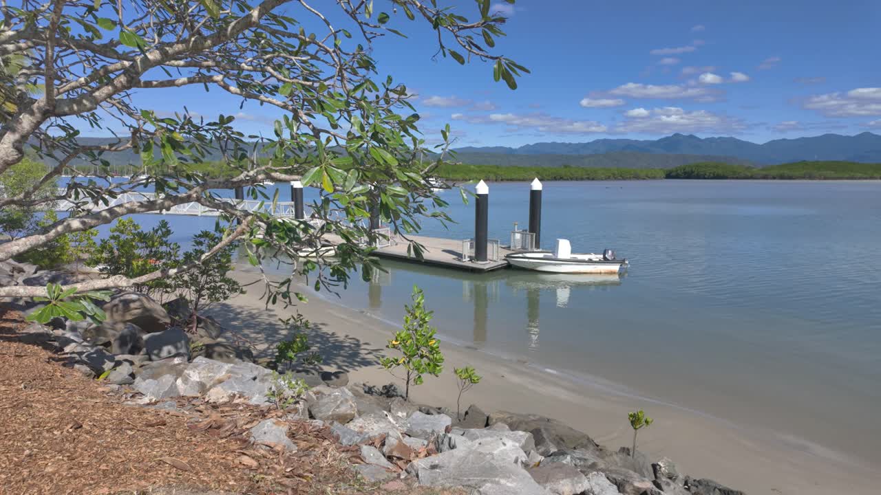 4K Sweeping view of a boat parked near a pontoon on a sandy beach in North Queensland, Australia