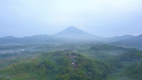 Langsame-Luftüberführung-Grüne-Landschaft-Mit-Kleinem-Dorf-Und-Nebligen-Bergen-In-Indonesien