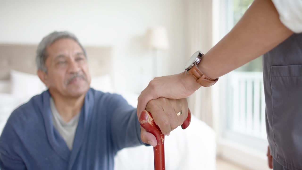 Un medico uomo aiuta un paziente anziano uomo a usare un bastone da passeggio a casa, in slow motion.