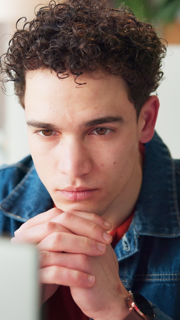Close-up of Young Man with Curly Hair Looking Intently at Screen