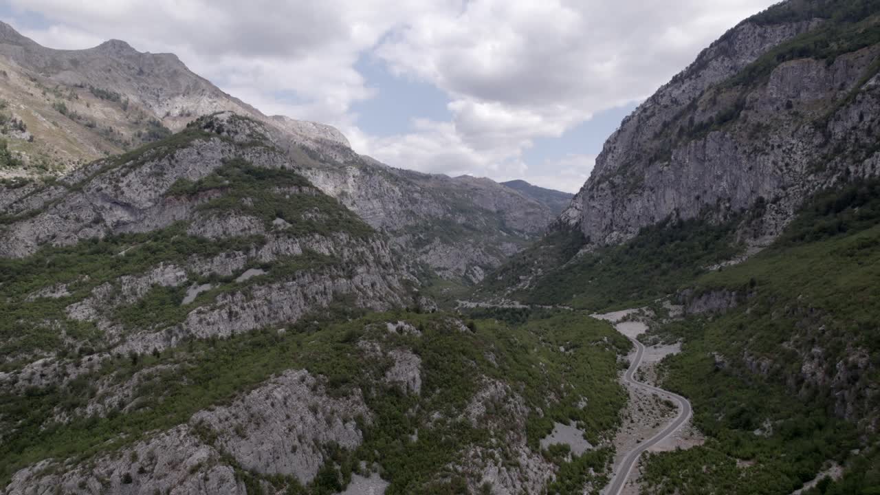 video de drones del avión frontal avanzando en la autopista sh20 en albania, a la altura de javor y mreg, camino de serpientes, se pueden ver pequeñas casas de la ciudad, cielo nublado