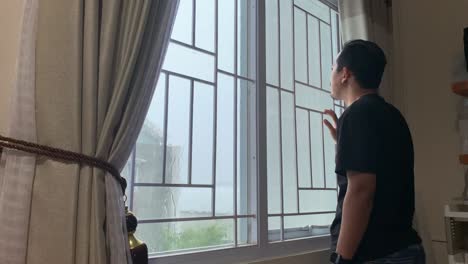 pensive sad asian man stands at the window