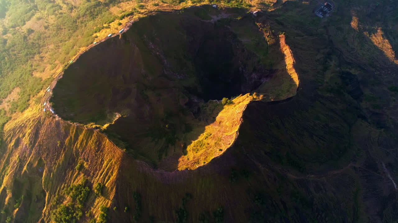 Majestic aerial footage of Mount Batur in Bali during sunrise. Glowing volcanic peaks, morning mist, and golden skies create a stunning scene—ideal for nature, travel, and adventure content