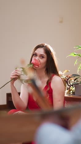 mujer con rosa posa para el artista en el estudio. atractiva modelo rubia en vestido de lujo se sienta mirando habilidoso diseñador dibujo retrato. trabajo creativo