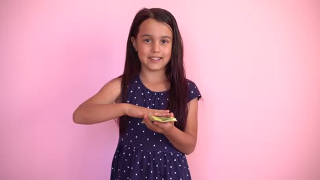 la pequeña niña caucásica recibe ingresos monetarios en billetes de dólar en efectivo. niño feliz divirtiéndose, sonriendo, mirando a la cámara.