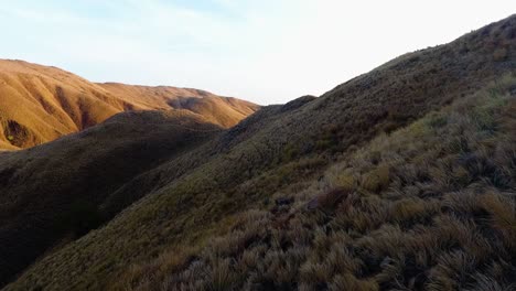 Los-Drones-De-La-Isla-De-Komodo,-Indonesia,-Vuelan-Cerca-De-Una-Formación-Rocosa-De-Montaña-Durante-El-Amanecer-A-Través-Del-Sol-Y-Revelan-Un-Hermoso-Archipiélago-Con-Vistas-Al-Océano