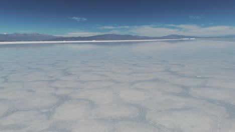 Drone-shot-flying-over-the-water-of-the-Salinas-Grandes-salt-flat-in-Jujuy,-Argentina