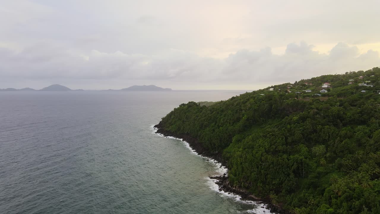 Immense sea next to island with trees,  clouds in the background on a cloudy day. Aerial drone shot