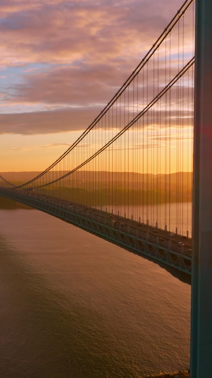 Acque calme dell'East River al tramonto. Splendida costruzione del ponte Whitestone con traffico intenso. Video verticale