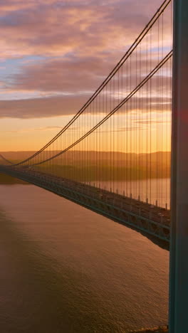 calm waters of east river at setting sun. beautiful construction of whitestone bridge with quick traffic. vertical video