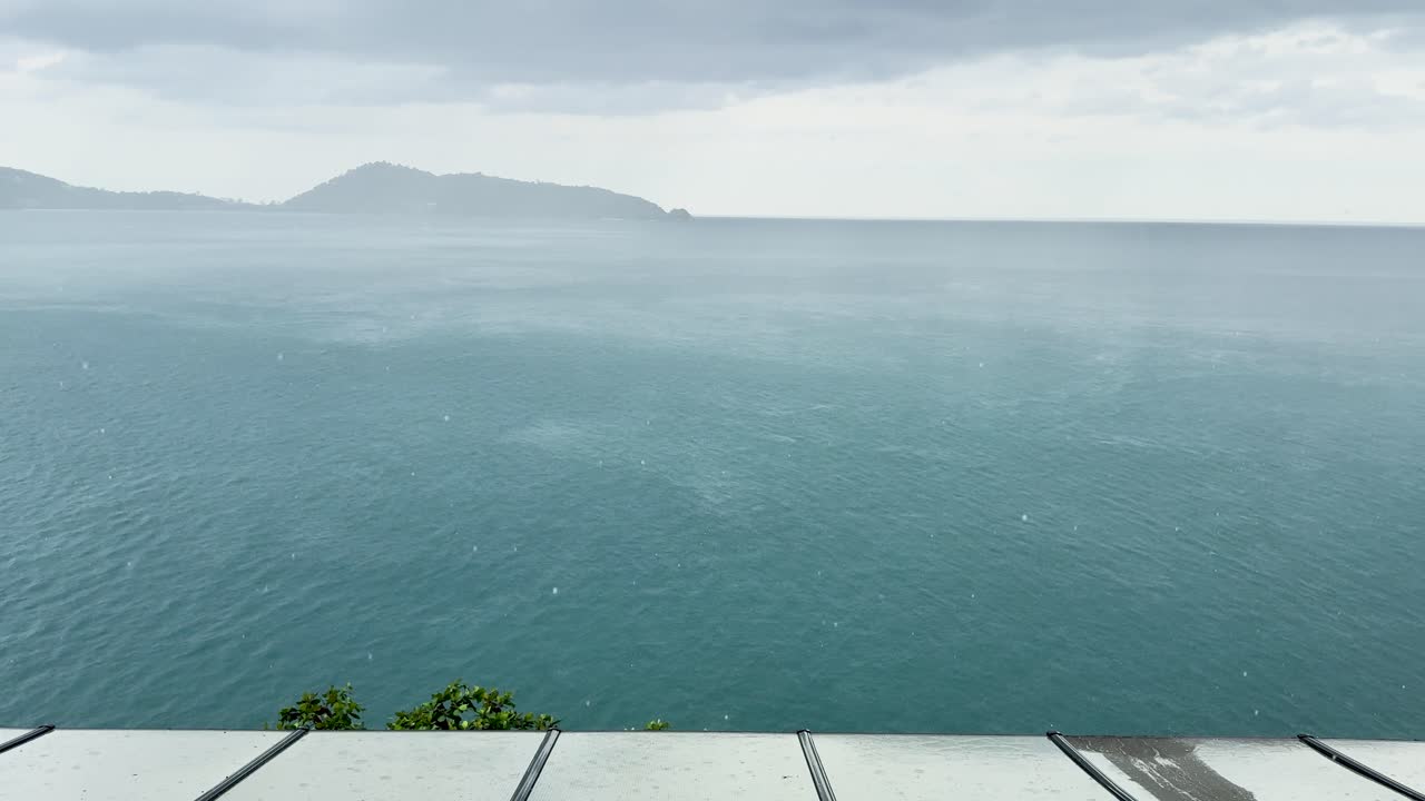 A storm approaches over the sea, viewed from a restaurant in Phuket, Thailand. The atmosphere is moody and dramatic