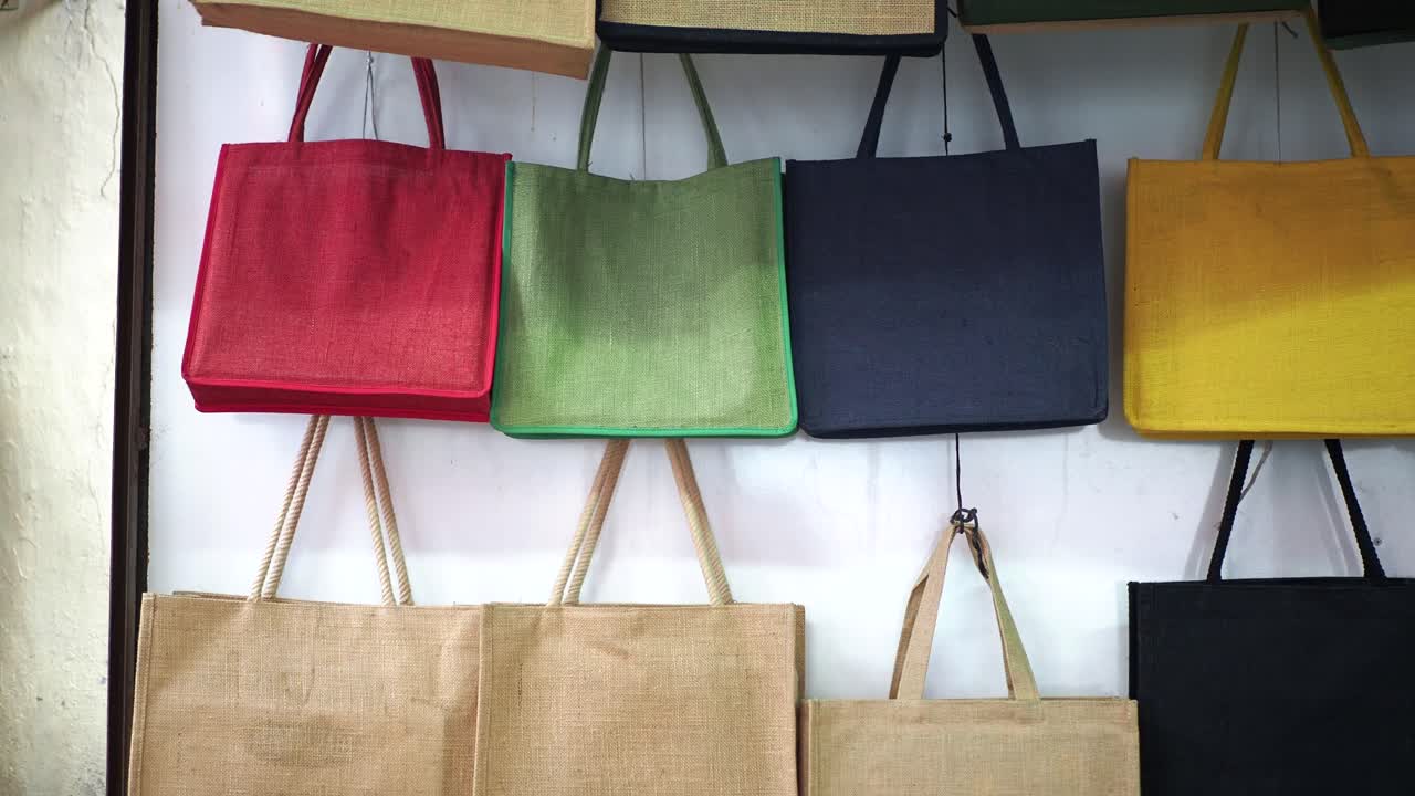 bolsas de compras de yute y lienzo coloridas colgando de una pared