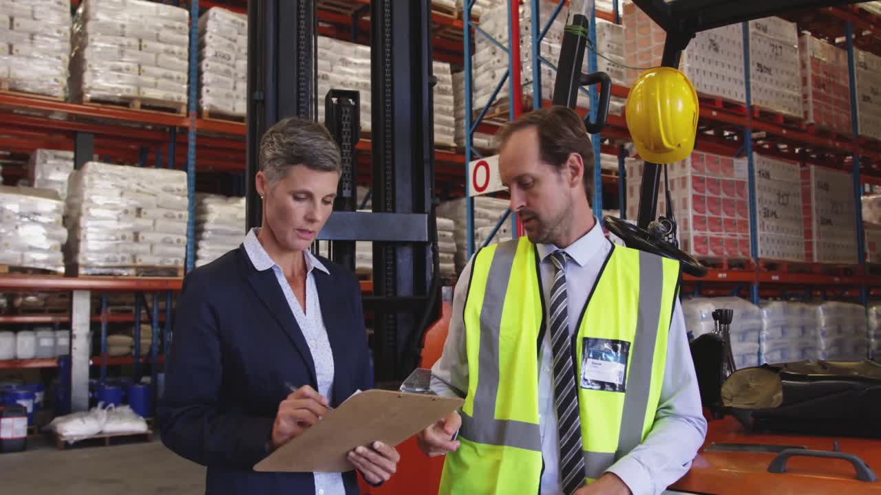 Male and female warehouse managers talking in a warehouse loading bay 4k