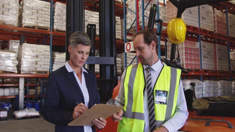 Male-and-female-warehouse-managers-talking-in-a-warehouse-loading-bay-4k