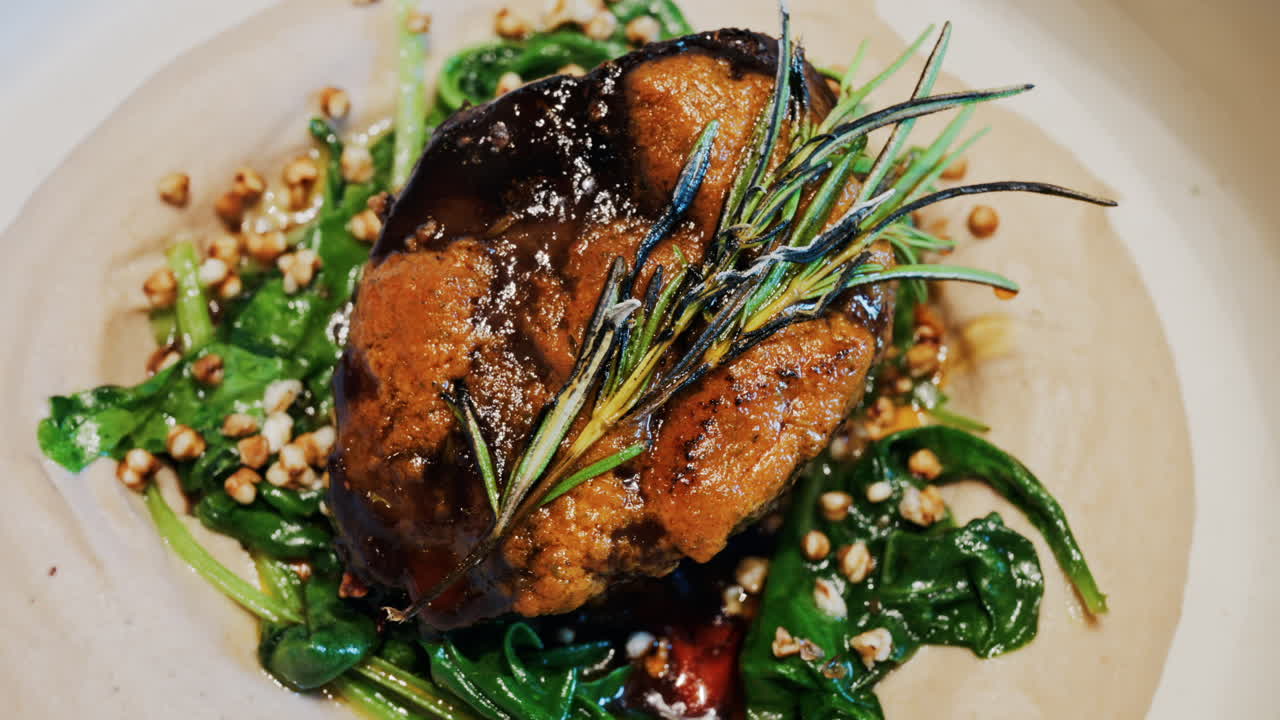 Close up of a beautifully plated beef filet, topped with a golden crust and garnished with rosemary