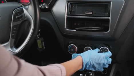 person adjusting car climate controls in gloves