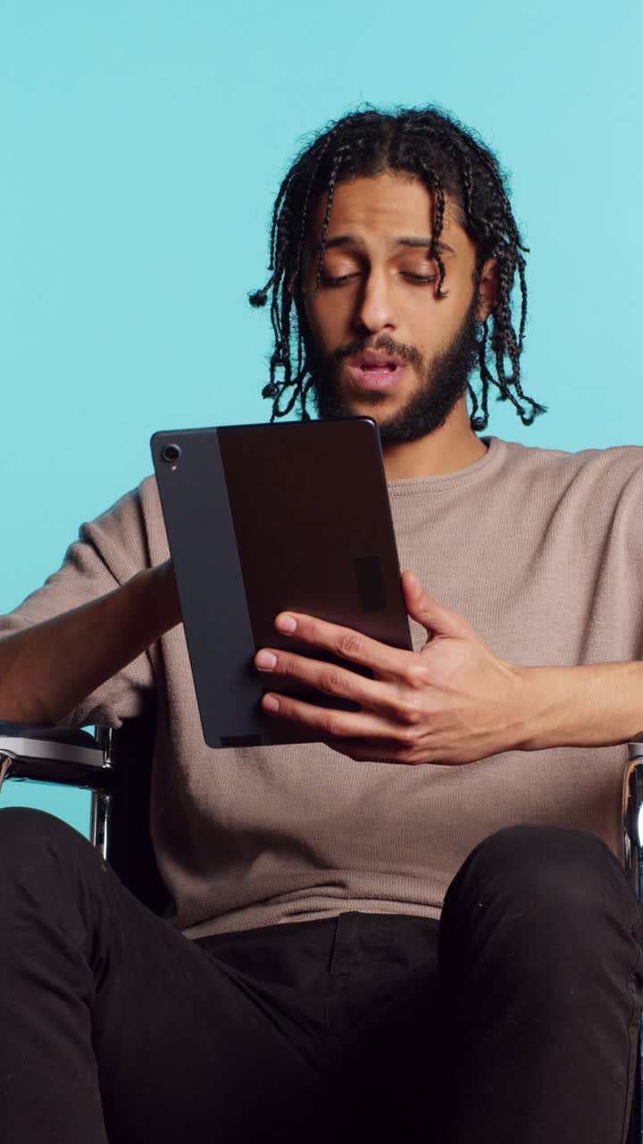 Vertical video Person with paraplegia using tablet for social media, studio background