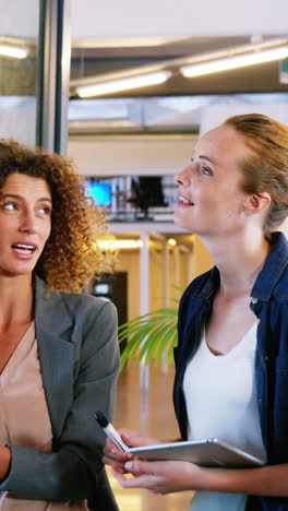 woman writing on sticky note and discussing with colleagues