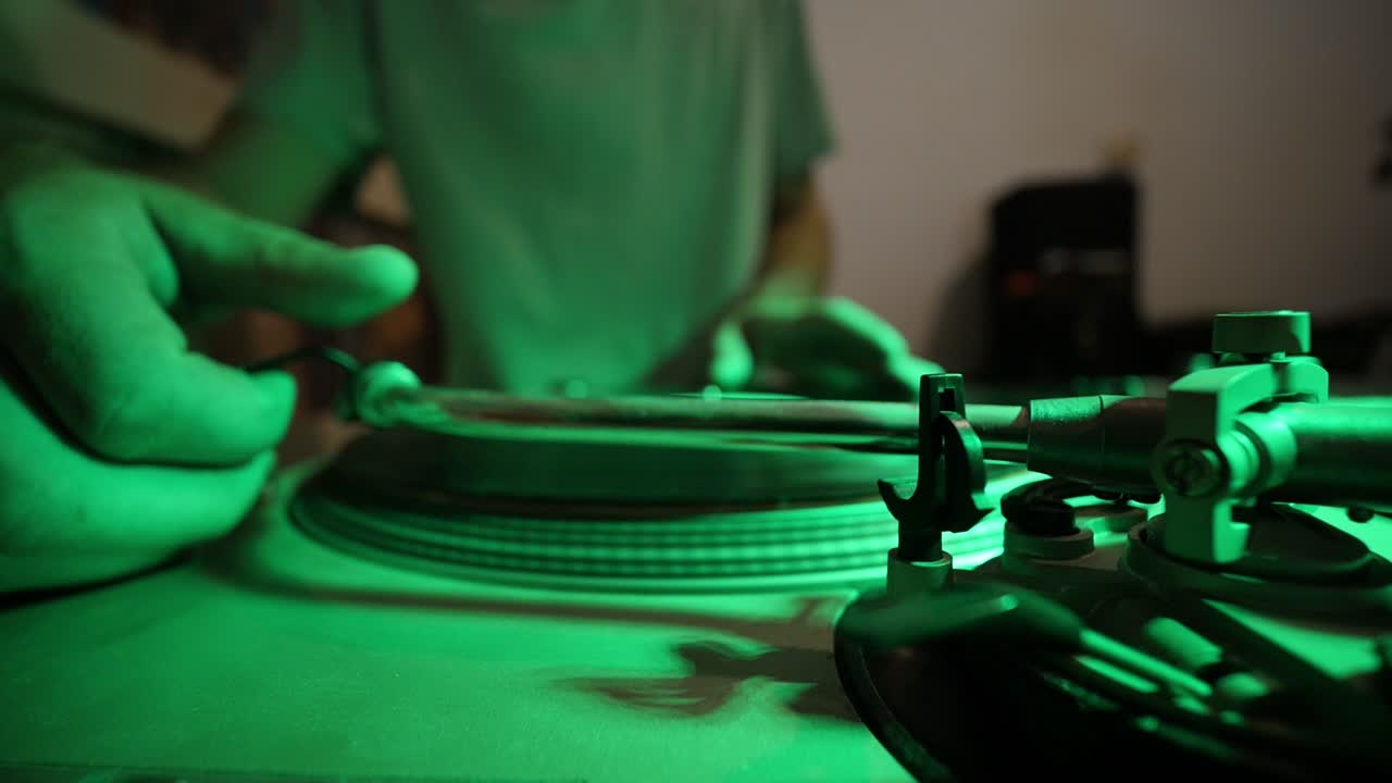dj poniendo vinilo en la mesa giratoria y colocando el lápiz óptico para iniciar el juego de música mientras las luces de colores parpadean ultra anchas