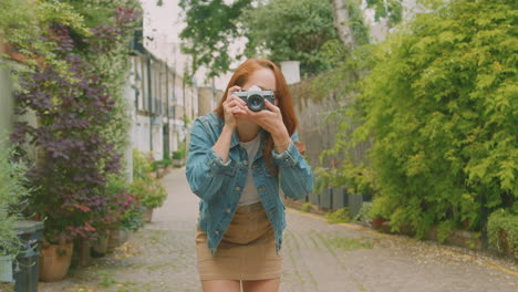 mujer joven en la ciudad tomando una foto con una cámara digital para publicarla en las redes sociales