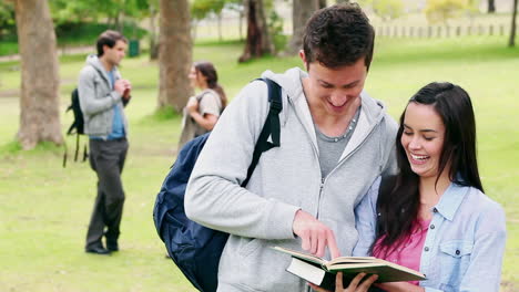 dos amigos riendo mientras leen un libro antes de señalar una página y sonreír