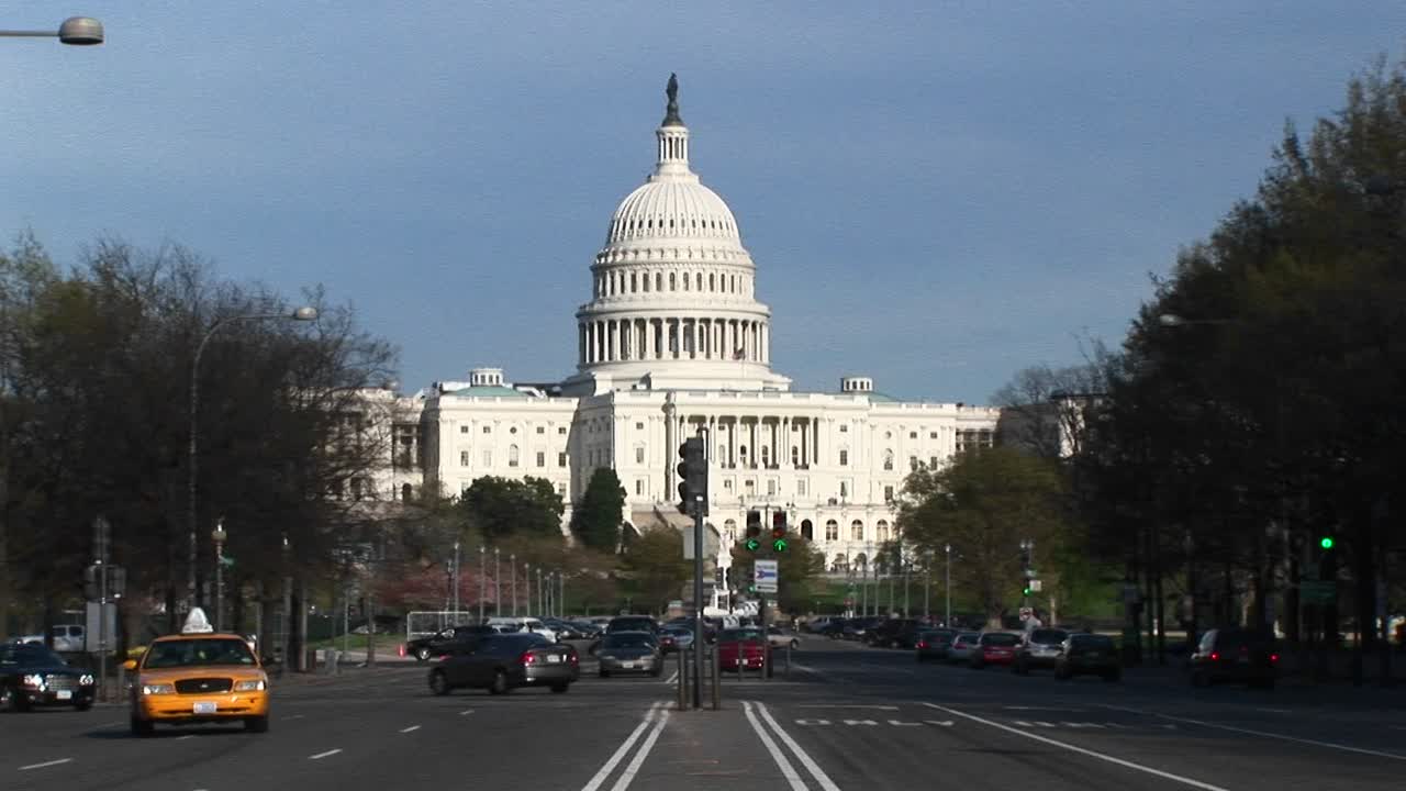 el tráfico fluye en muchas direcciones en las calles arboladas frente al edificio del capitolio de los estados unidos