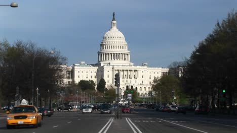 traffic flows in many directions on the treelined streets in front of the united states capitol building