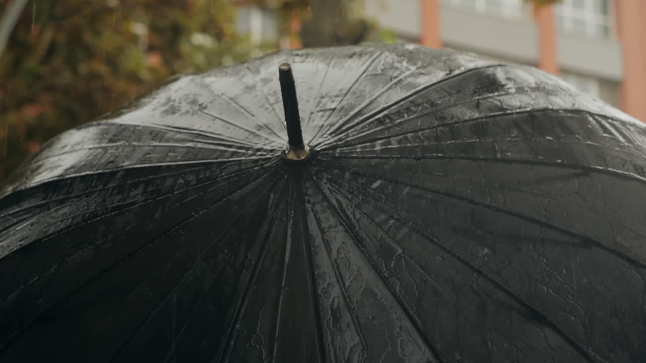 Business man tourist person with umbrella and raincoat on rainy european city street, lights reflecting, walking in Barcelona or Amsterdam during the rain