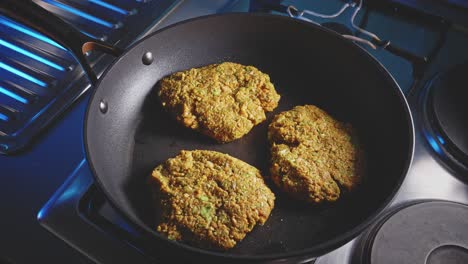 man flipping veggie patties and covering the non-stick frying pan with tempered glass, close-up shot