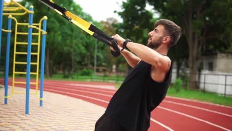 an athletic man doing push ups exercise using rubber belt to force strenth of workout on chest muscles and biceps