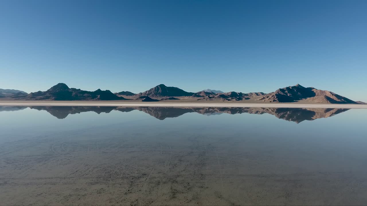 una toma aérea de drones revela agua tranquila que cubre las salinas de bonneville y refleja montañas distantes
