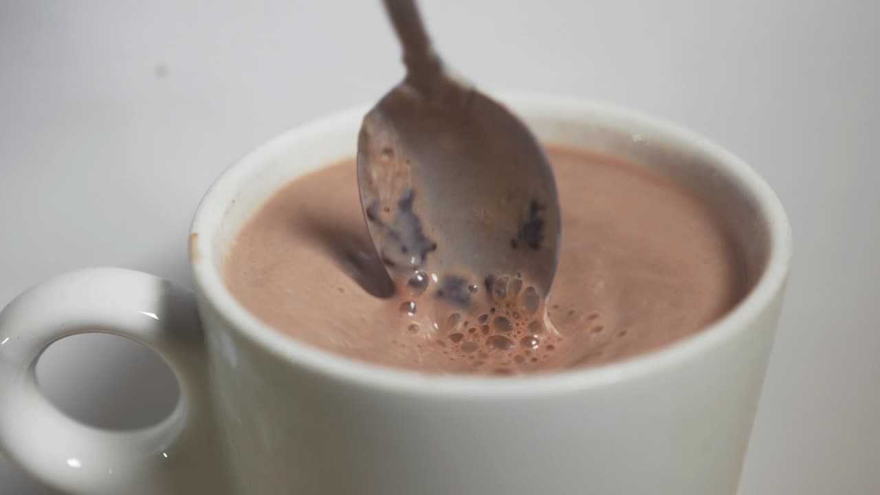agitando una bebida de chocolate caliente sacando una cuchara a cámara lenta