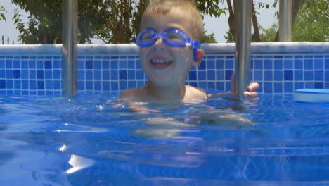 niño sonriente con gafas de protección en la piscina