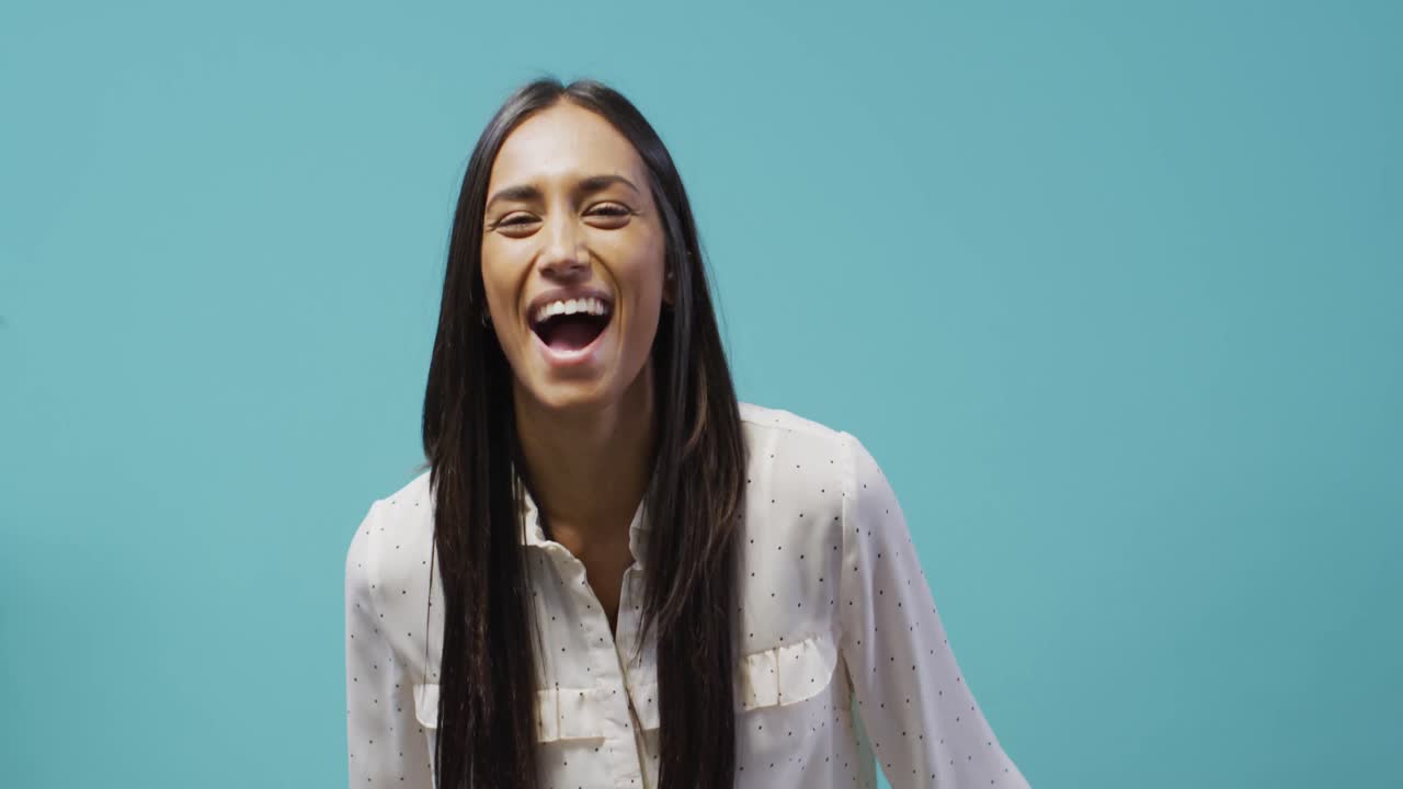 video di una donna bi-razziale felice che guarda la telecamera sullo sfondo blu