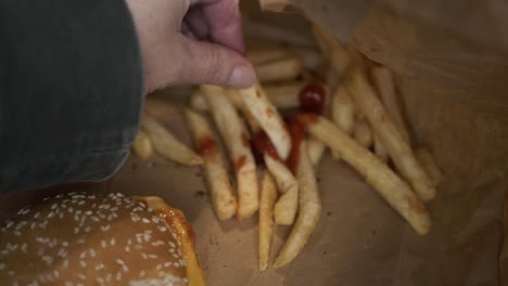 Hand-eating-cheeseburger-meal-with-fries-medium-shot