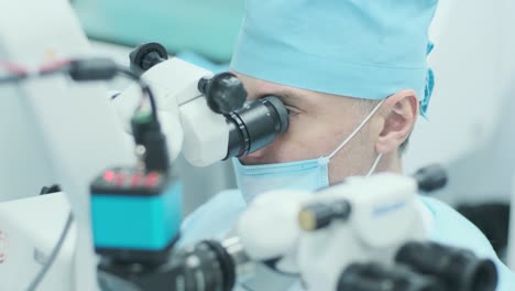 cirujano mirando al microscopio en el ojo de la paciente femenina en la sala de operaciones. médico usando el microscopio durante el proceso de cirugía ocular, tratamiento de cataratas y corrección de dioptría.